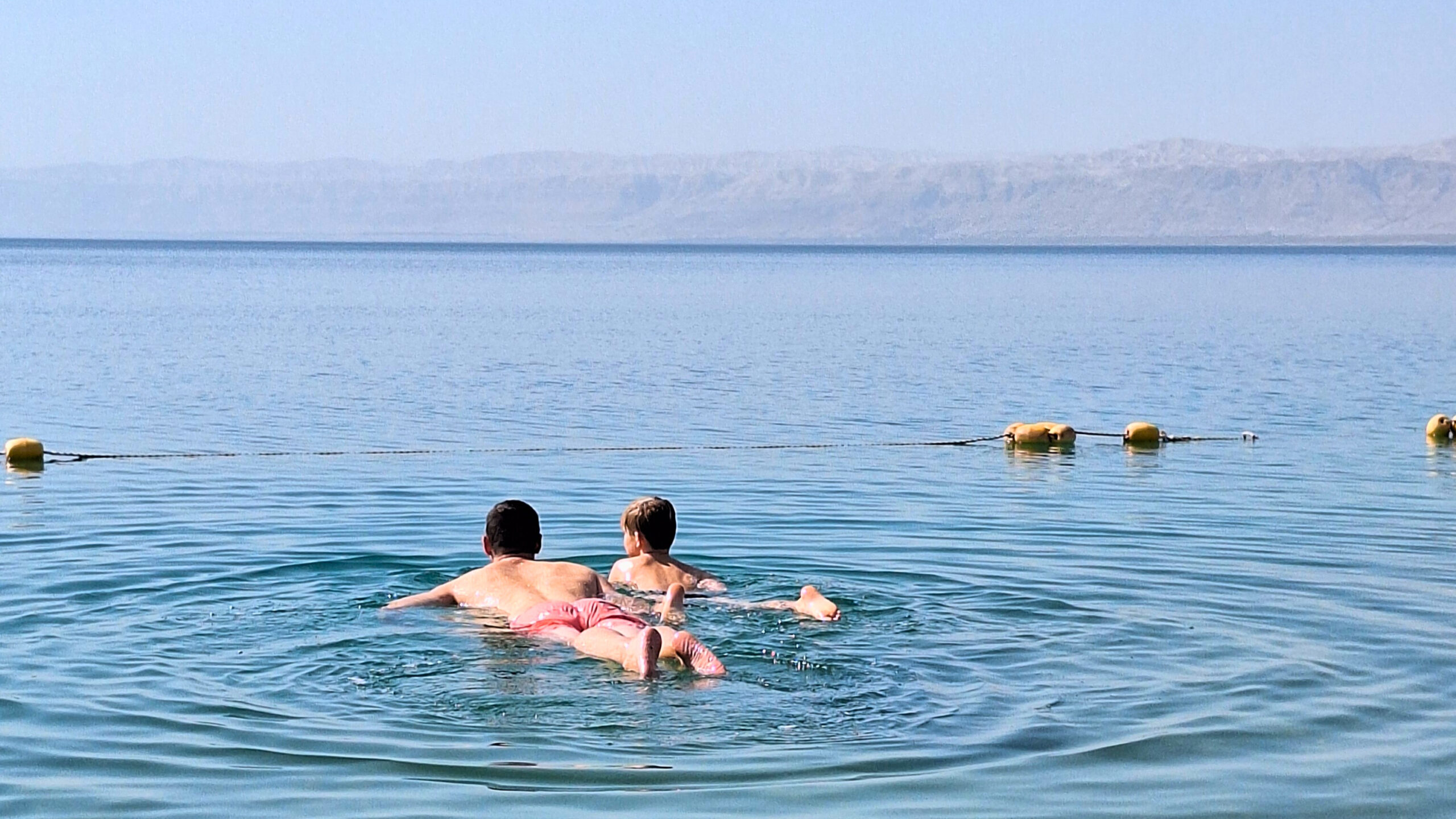 Vader en zoon zwemmen in de Dode Zee