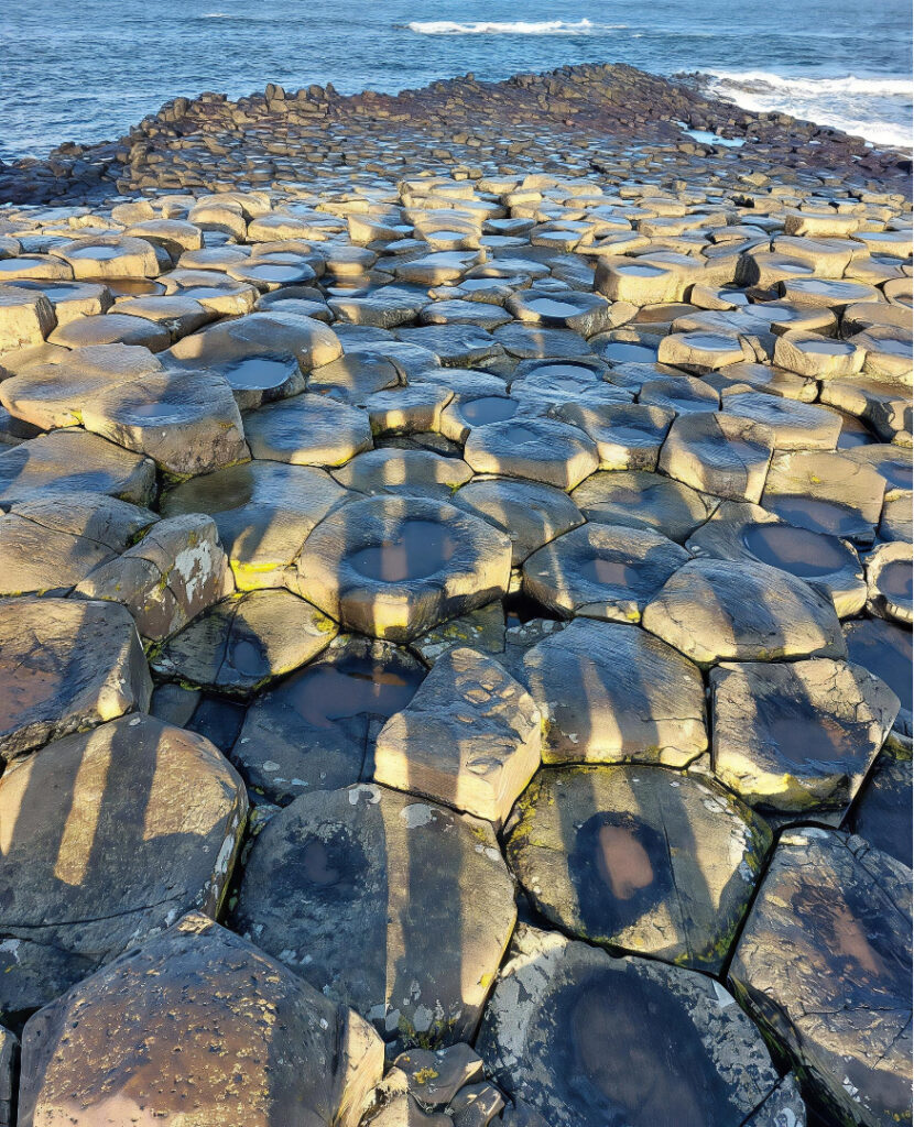 Vakantie met kinderen aan de Giant's Causeway, Noord-Ierland, familie's shaduw op de stenen