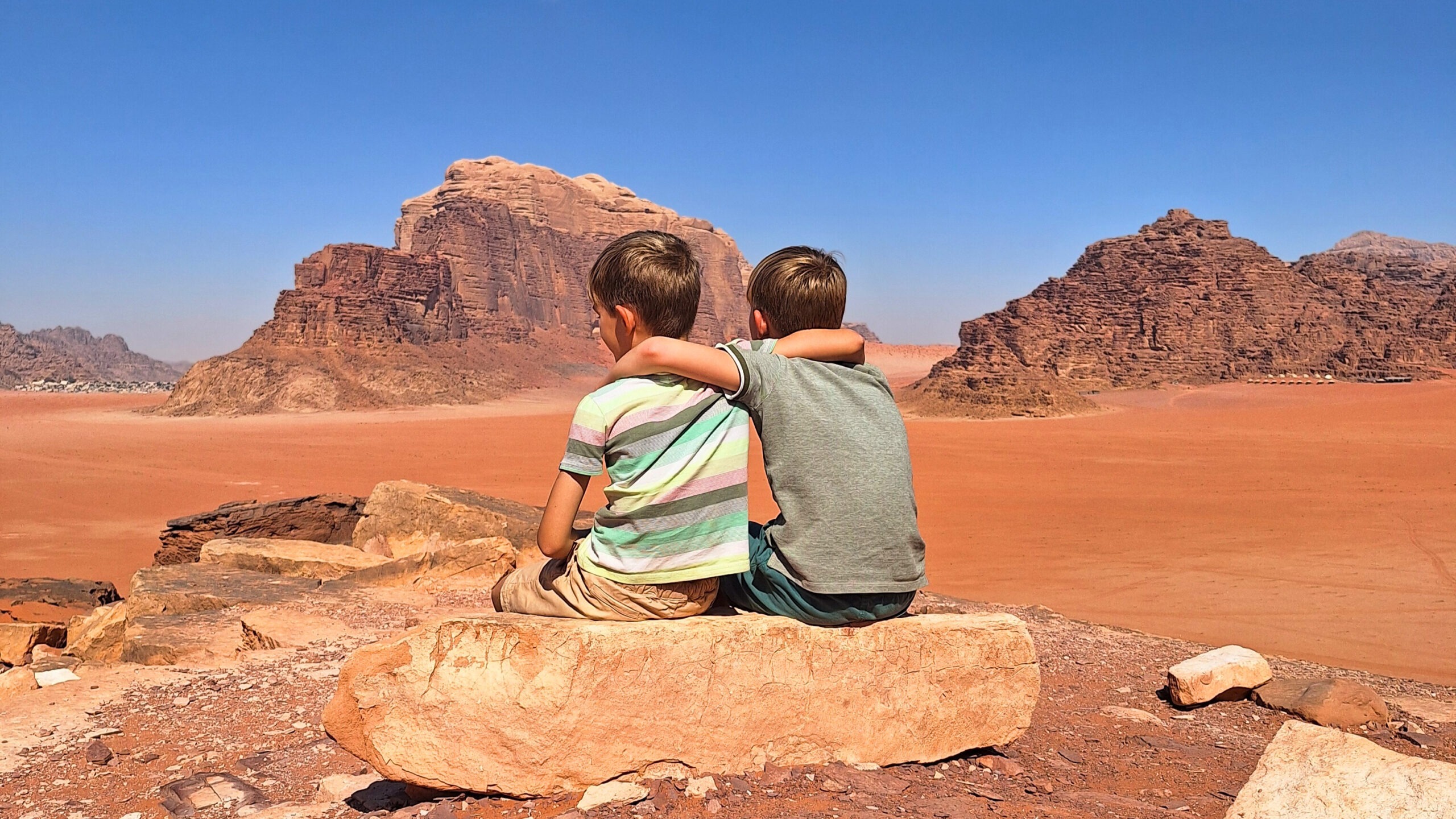 Jongens op een steen in Wadi Rum; Jordanië; avontuur